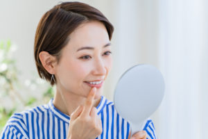 恵比寿デンタルクリニック東京｜歯がしみる原因とは｜鏡で歯を確認する女性の画像